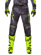 Alpinestars 2025 Racer Hollow Pants, motorcykelbyxor för motocross, mörkgrå med neongula detaljer, gula stjärnlogotyper, kombinerad med neongula stövlar och svarta handskar, skyddande sportdesign