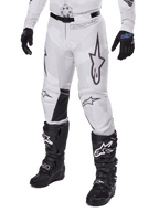 Alpinestars 2025 Racer Hollow Pants, Motocross Pants, White and Grey Camo, featuring large black outlined star logos and black leather inner knee panels, worn with black motocross boots and gloves, durable design for off-road racing.