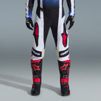 Alpinestars 2026 Techstar Knif-utrustningsset, motocrossutrustning, svarta och vita byxor med stora röda stjärnlogotyper, bärs med svarta och röda racingstövlar och svarta handskar, professionell atletisk passform för offroad-prestanda