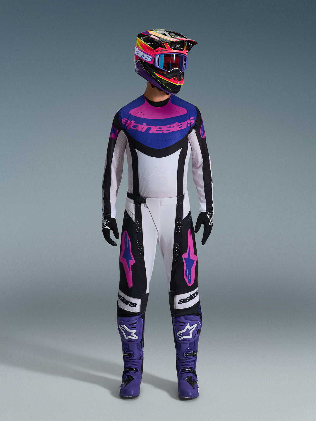 Alpinestars 2026 Techstar Knif Gear Set, Complete Motocross Outfit, White Black Purple and Pink, worn with a multi-colored helmet, blue goggles, purple boots, and black gloves, coordinated high-performance kit for off-road racing