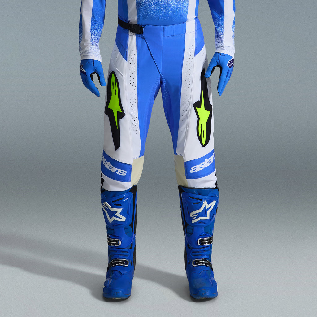 Alpinestars 2026 Techstar Knif utrustningsset, blå och vita motocrossbyxor med neongula logotyper, matchande blå stövlar och handskar, professionell atletisk racingoutfit för terrängkörning