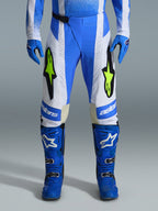 Alpinestars 2026 Techstar Knif-byxor, motocrossbyxor, UCLA-blå, svarta och gul fluo, bärs med matchande blå handskar och stövlar, med vita paneler och livfulla logotyper i gul fluo, ergonomisk racingpassform för terrängprestanda
