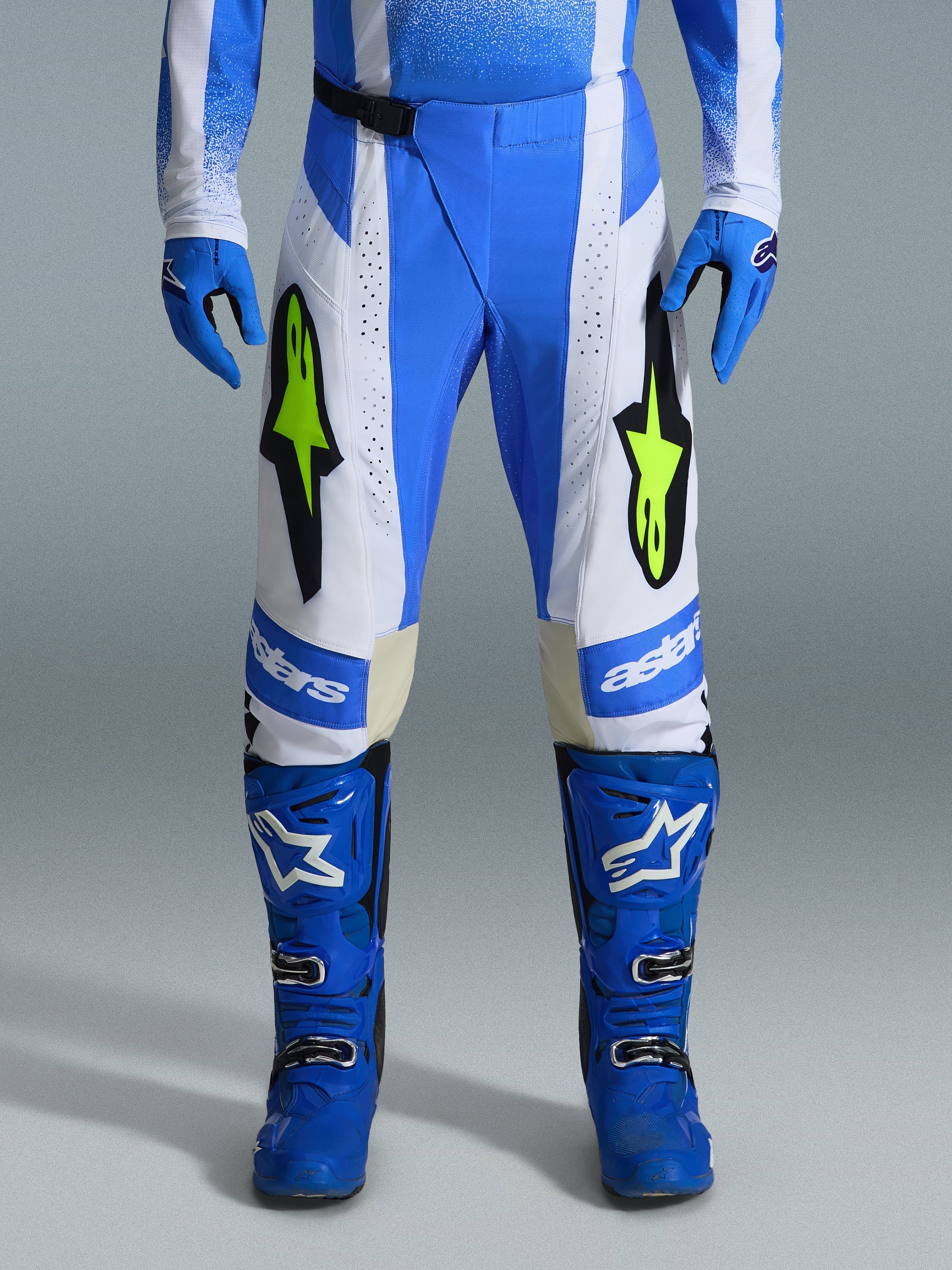 Alpinestars 2026 Techstar Knif-byxor, motocrossbyxor, UCLA-blå, svarta och gul fluo, bärs med matchande blå handskar och stövlar, med vita paneler och livfulla logotyper i gul fluo, ergonomisk racingpassform för terrängprestanda
