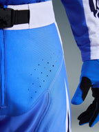 Alpinestars 2026 Techstar Knif-byxor, motocrossbyxor, Ucla-blå och svarta, närbild av lår med laserskurna perforeringar och SX2 magnetiskt midjespänne, teknisk konstruktion för terrängkörning