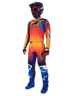 Motocrossförare i komplett racingutrustning, Alpinestars 2025 Fluid Wurx-byxor och matchande tröja med en flerfärgad toning i orange, rött och lila, svart hjälm med röda goggles, blå och svarta stövlar, röda och svarta handskar, koordinerad outfit för terrängkörning