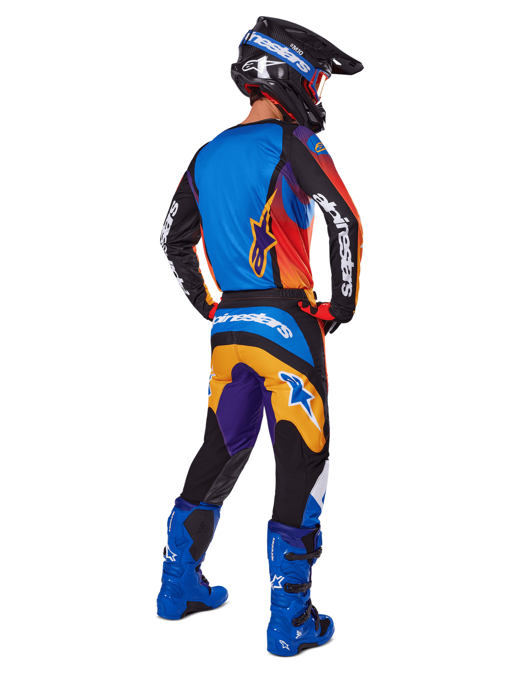 Motocrossförare sedd bakifrån i Alpinestars 2025 Fluid Wurx-byxor, flerfärgad design med blå, orange, gula och lila detaljer, matchande tröja, klart blå stövlar och svart hjälm, komplett utrustning för terrängkörning
