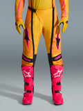 Alpinestars 2026 Techstar Nomur-byxor, motocrossbyxor, orange, gula och rosa, bärs med matchande gula handskar och starkt rosa racingstövlar, med svarta paneler och framträdande rosa Alpinestars-logotyp, teknisk racingutrustning för terrängkörning