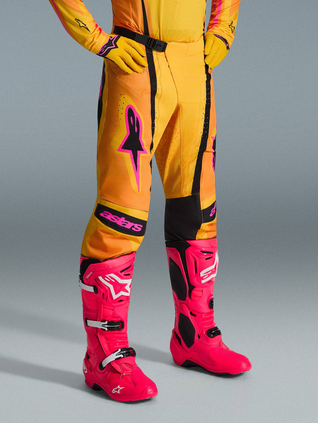 Alpinestars 2026 Techstar Nomur-byxor, motocrossbyxor, orange, gula och rosa, bärs med matchande gul tröja och handskar samt starkt rosa stövlar, atletisk tävlingspassform med rosa logotyper och svart magnetiskt spänne, färgstark utrustning för terrängtävling