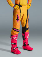 Alpinestars 2026 Techstar Nomur-byxor, motocrossbyxor, orange, gula och rosa, bärs med matchande gul tröja och handskar samt starkt rosa stövlar, atletisk tävlingspassform med rosa logotyper och svart magnetiskt spänne, färgstark utrustning för terrängtävling