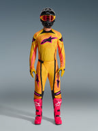 Motocrossförare i ett komplett Alpinestars 2026 Techstar Nomur-ställ, orange, gul och rosa tröja och byxor, matchande gula och rosa handskar, knallrosa racingstövlar och svart hjälm med rosa goggles, koordinerad högpresterande motocrossoutfit.