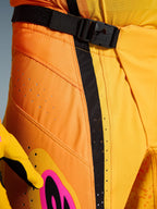 Alpinestars 2026 Techstar Nomur byxor, motocrossbyxor, orange, gul och rosa, närbild av midjan med det magnetiska SX2-spännet, svart justeringsrem och laserskurna ventilationsperforeringar på slitstarkt ripstop-material