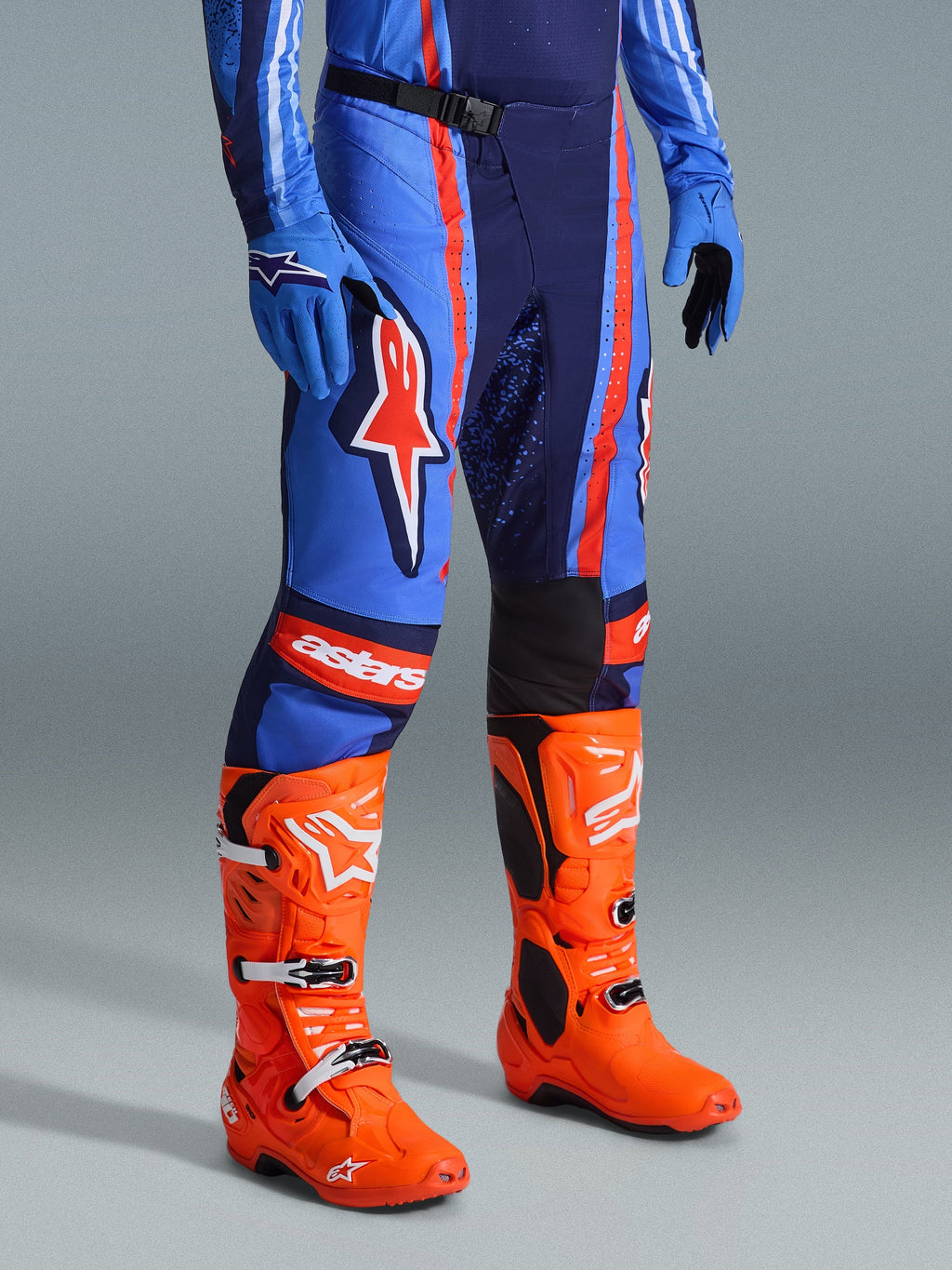 Alpinestars 2026 Techstar Nomur byxor, motocrossbyxor, mörkblå, orange och UCLA-blå, bärs med klarorange motocross-stövlar och matchande blå utrustning, framträdande logotyper och konstruktion i flera material för terrängkörning.