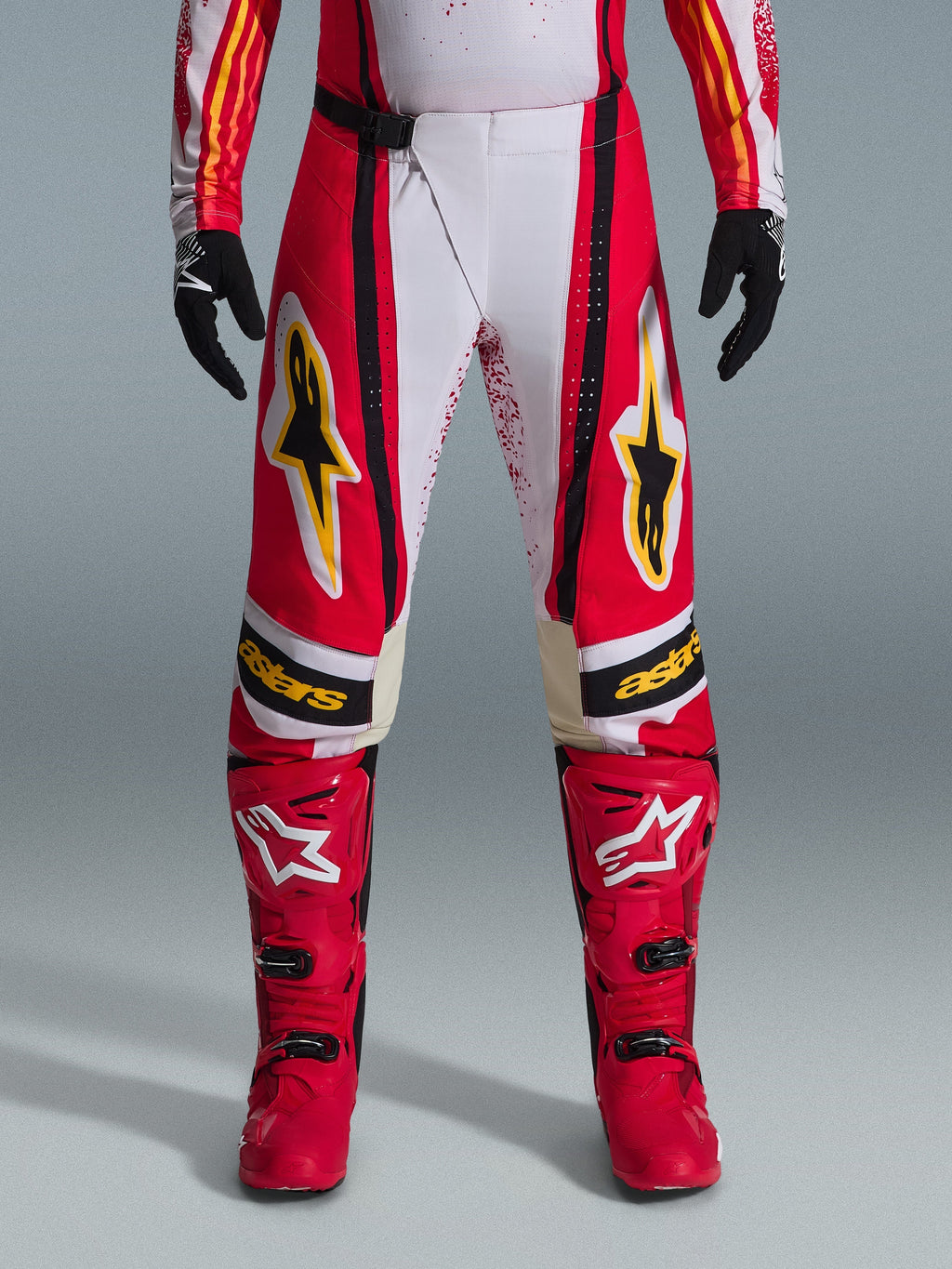 Alpinestars 2026 Techstar Nomur byxor, motocrossbyxor, röda och vita med svarta och gula detaljer, bärs med matchande röda stövlar och svarta handskar, högpresterande racingutrustning för terrängkörning