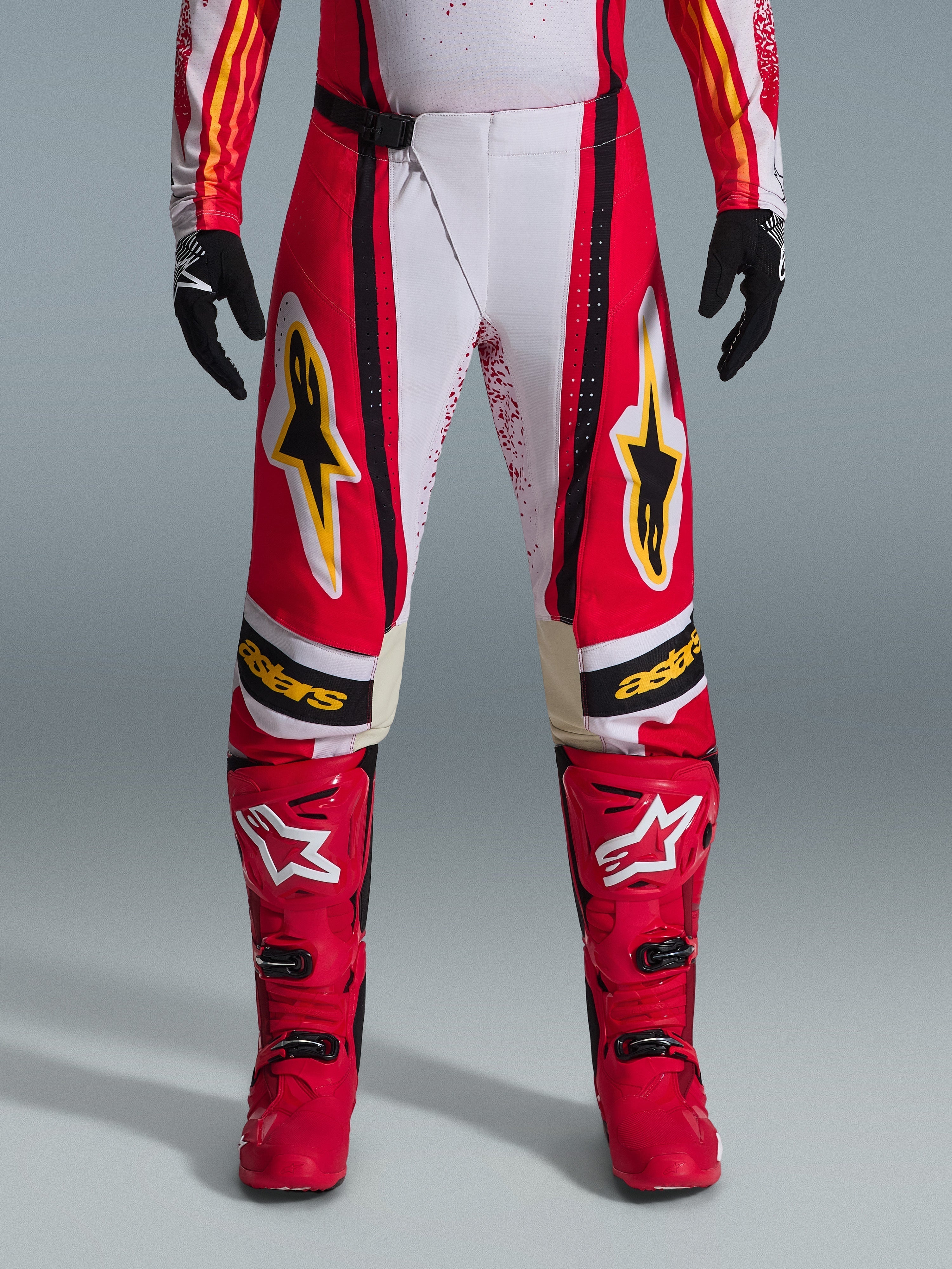 Alpinestars 2026 Techstar Nomur byxor, motocrossbyxor, röda och vita med svarta och gula detaljer, bärs med matchande röda stövlar och svarta handskar, högpresterande racingutrustning för terrängkörning