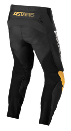 Alpinestars Techstar Quadro-byxor, motocrossbyxor, svarta, gula och orange, bakvy med gul 'ASTARS'-logotyp på linningen, svarta mesh-insatser för ventilation och ergonomiska gula och orangea knäpaneler för hållbarhet vid terrängkörning.