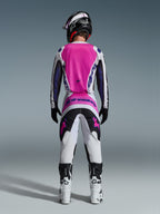 Motocross rider from the back wearing Alpinestars 2026 Fluid Grid Pants and matching jersey, Pink White and Black with Purple branding, Black helmet, White and Black boots, coordinated racing outfit for off-road motocross