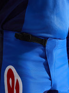 Alpinestars 2026 Fluid Grid byxor, motocrossbyxor, blå och röda, närbild av det svarta midjespännet med spärrfunktion, slitstarkt blått polytyg med röd och vit logotyp, konstruerade för terrängkörning