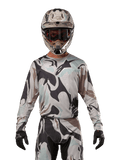 Alpinestars 2024 Racer Tactical tröja, motocrosströja, kamouflagemönstret Iron Camo Dust Gray, förare som bär matchande hjälm och goggles med svarta handskar, teknisk utrustning för terrängkörning