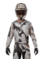 Alpinestars 2024 Racer Tactical tröja, motocrosströja, kamouflagemönstret Iron Camo Dust Gray, förare som bär matchande hjälm och goggles med svarta handskar, teknisk utrustning för terrängkörning