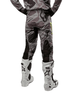 Alpinestars 2024 Racer Tactical byxor, motocrossbyxor, Cast Gray Camo Magnet, baksida som visar kamouflagemönstret och svarta andningsbara stretchzoner, bärs med vita och svarta motocross-stövlar, designade för terrängkörning