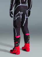Alpinestars 2026 Fluid Apex Pants, Motocross Pants, Black and Gray, rear view featuring large white Alpinestars logos on the seat, worn with bright red and pink boots, durable 600D polyfabric construction for off-road performance