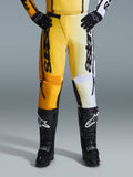 Alpinestars 2026 Fluid Apex byxor, motocrossbyxor, gula och svarta, färgdelad design med gula och vita paneler, framträdande vertikal 'astars'-logotyp, bärs med svarta motocross-stövlar och handskar, prestandautrustning för terrängkörning