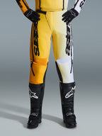 Alpinestars 2026 Fluid Apex byxor, motocrossbyxor, gula och svarta, färgdelad design med gula och vita paneler, framträdande vertikal 'astars'-logotyp, bärs med svarta motocross-stövlar och handskar, prestandautrustning för terrängkörning