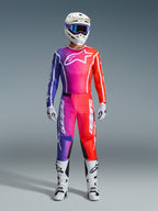 Motocrossförare iklädd 2026 Fluid Apex-byxor och matchande tröja, lila och orange färgtoning, vit hjälm med goggles, vita stövlar och handskar, koordinerad Alpinestars-racingutrustning för offroad-prestanda.