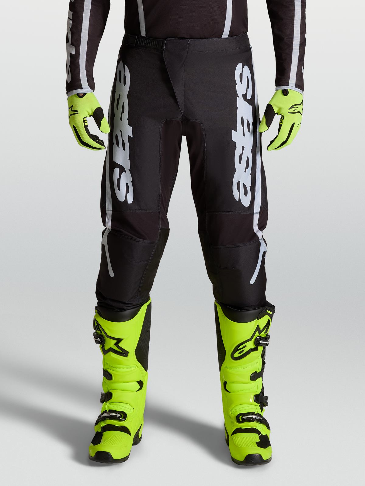 Alpinestars 2027 Fluid Apex V2 byxor, herrmotocrossbyxor i svart och silver med ergonomiska stretchpaneler, på modell.