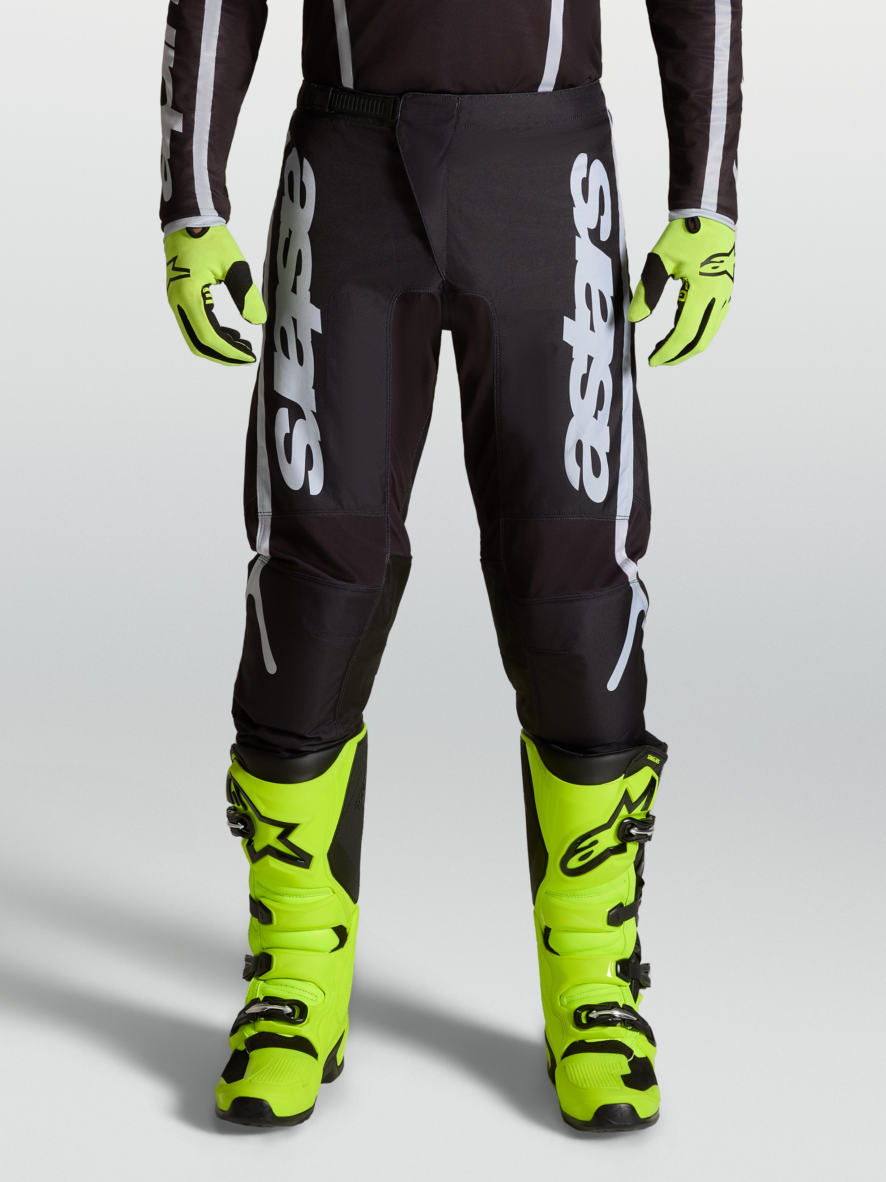Alpinestars 2027 Fluid Apex V2 byxor, herrmotocrossbyxor i svart och silver med ergonomiska stretchpaneler, på modell.
