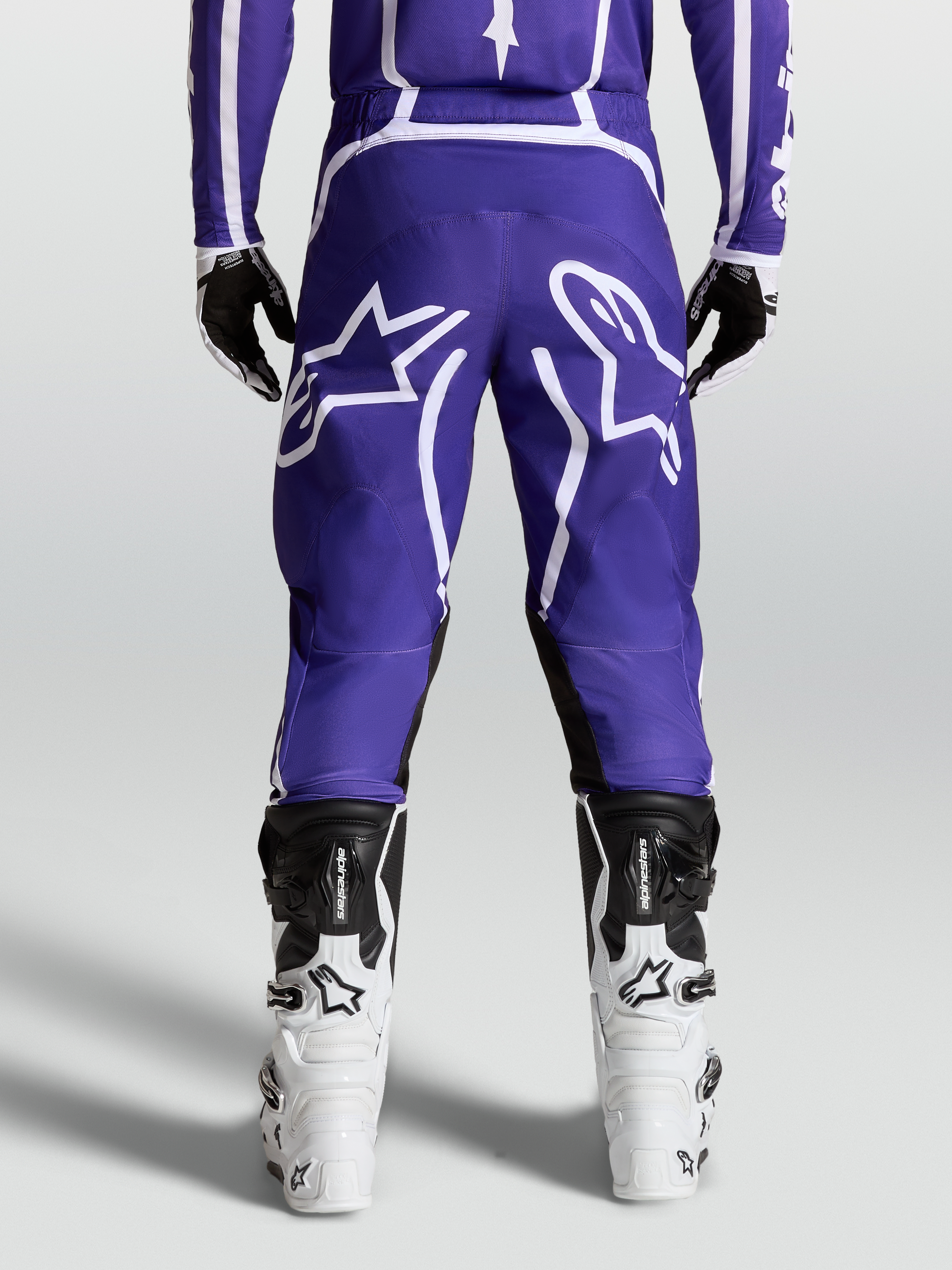 Alpinestars Fluid Apex V2 byxor, MX-byxor för herr, mörkblå och vita, hållbar 600D polytygskonstruktion med förböjda ben, vy bakifrån på modell med stövlar
