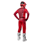 Alpinestars 2024 Racer Hoen-byxor och matchande tröja i Mars Red Burgundy, bakifrån vy av en motocrossförare i full utrustning med röd hjälm och vita stövlar, atletisk passform och logotypdetaljer för terrängkörning