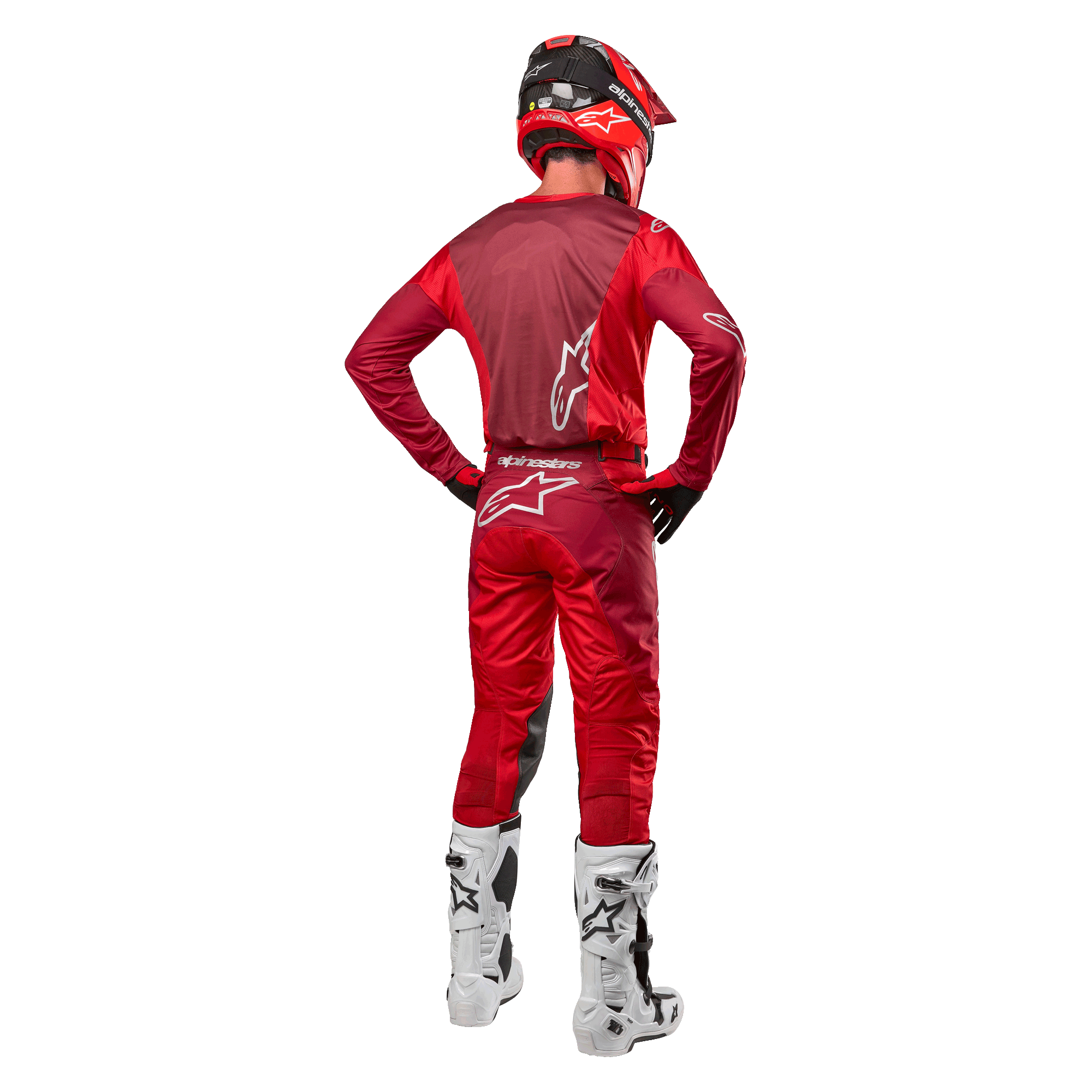Alpinestars 2024 Racer Hoen-byxor och matchande tröja i Mars Red Burgundy, bakifrån vy av en motocrossförare i full utrustning med röd hjälm och vita stövlar, atletisk passform och logotypdetaljer för terrängkörning