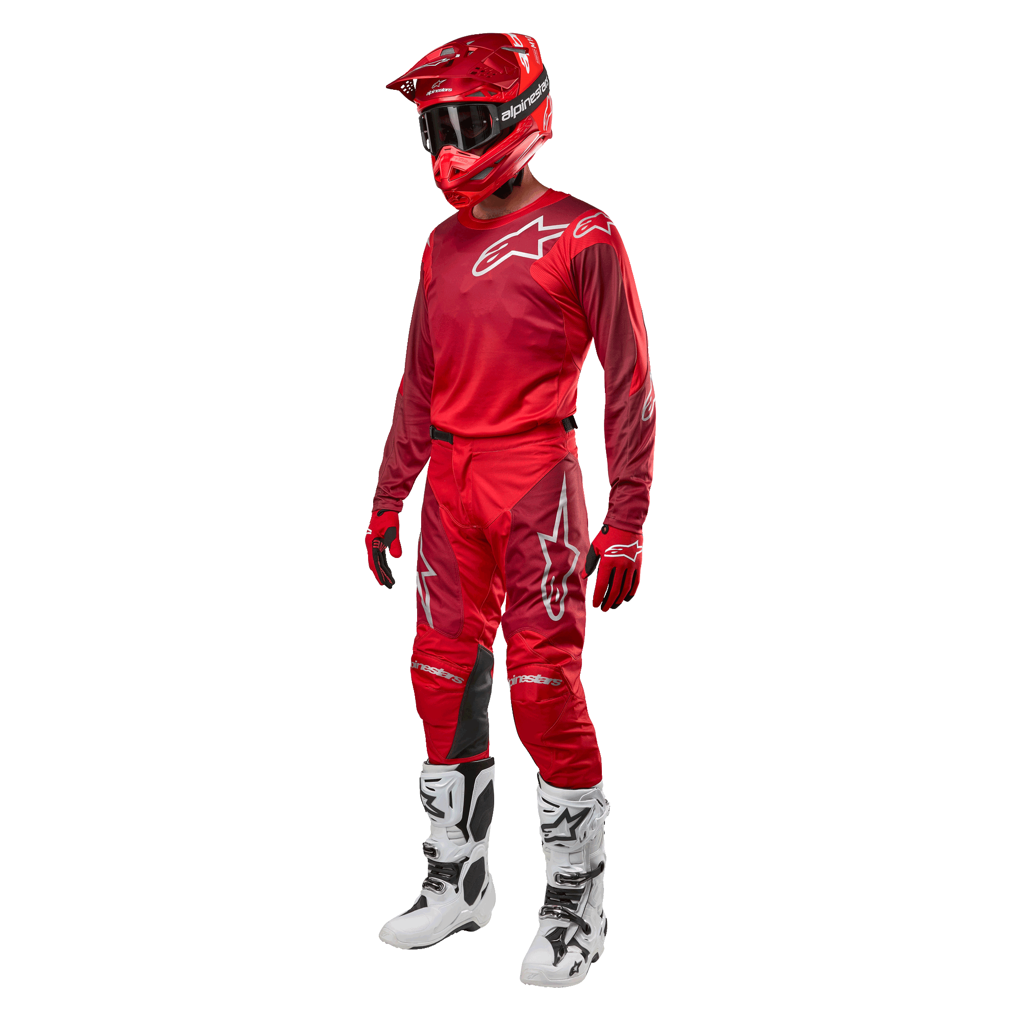 Motocrossförare i komplett racingutrustning, Alpinestars 2024 Racer Hoen byxor och tröja i Mars Red Burgundy, röd hjälm, röda handskar och vita och svarta stövlar, matchande outfit för terrängkörning