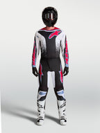 Alpinestars Fluid Drag byxor, motocrossbyxor för herrar, svarta och vita med röd fluo-grafik och ljusblå detaljer, ergonomisk passform för terrängkörning, visas på modell med matchande tröja och stövlar.