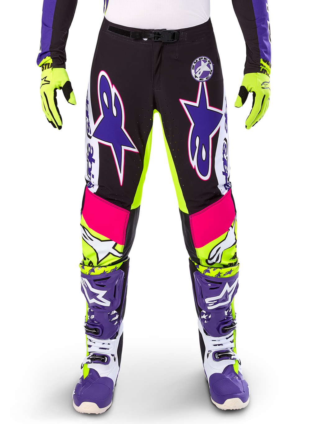 Alpinestars Limited Edition Supertech Dirt Studios byxor, motocrossbyxor, vit, lila och neongul, med svarta paneler samt neongula och rosa detaljer, stora lila stjärnlogotyper, visas med matchande neongula handskar och lila racingstövlar, hållbara kläder för terrängkörning