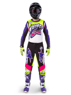 Motocrossförare i komplett racingutrustning, Limited Edition Supertech Dirt Studios-tröja och byxor i vitt, lila och gul fluo, svart hjälm med goggles, lila och vita stövlar, matchande färgstark outfit för motocross
