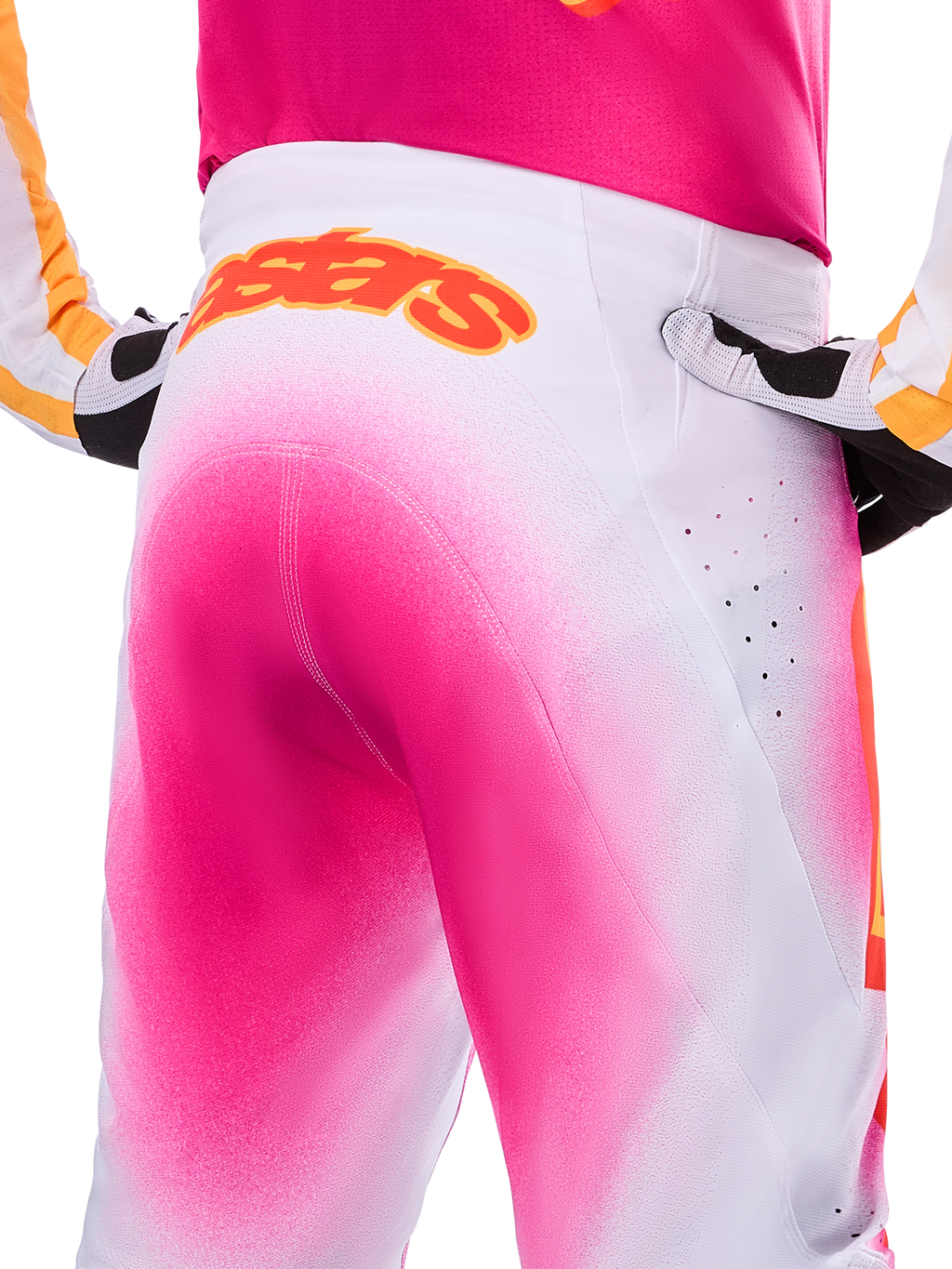 Alpinestars Limited Edition Supertech AFD MIG-byxor, motocrossbyxor, rosa fluo och vita med spraymålad fade-effekt, stor orange Alpinestars-logotyp på bakre linningen, närbild som visar atletisk passform och ventilationsperforeringar.