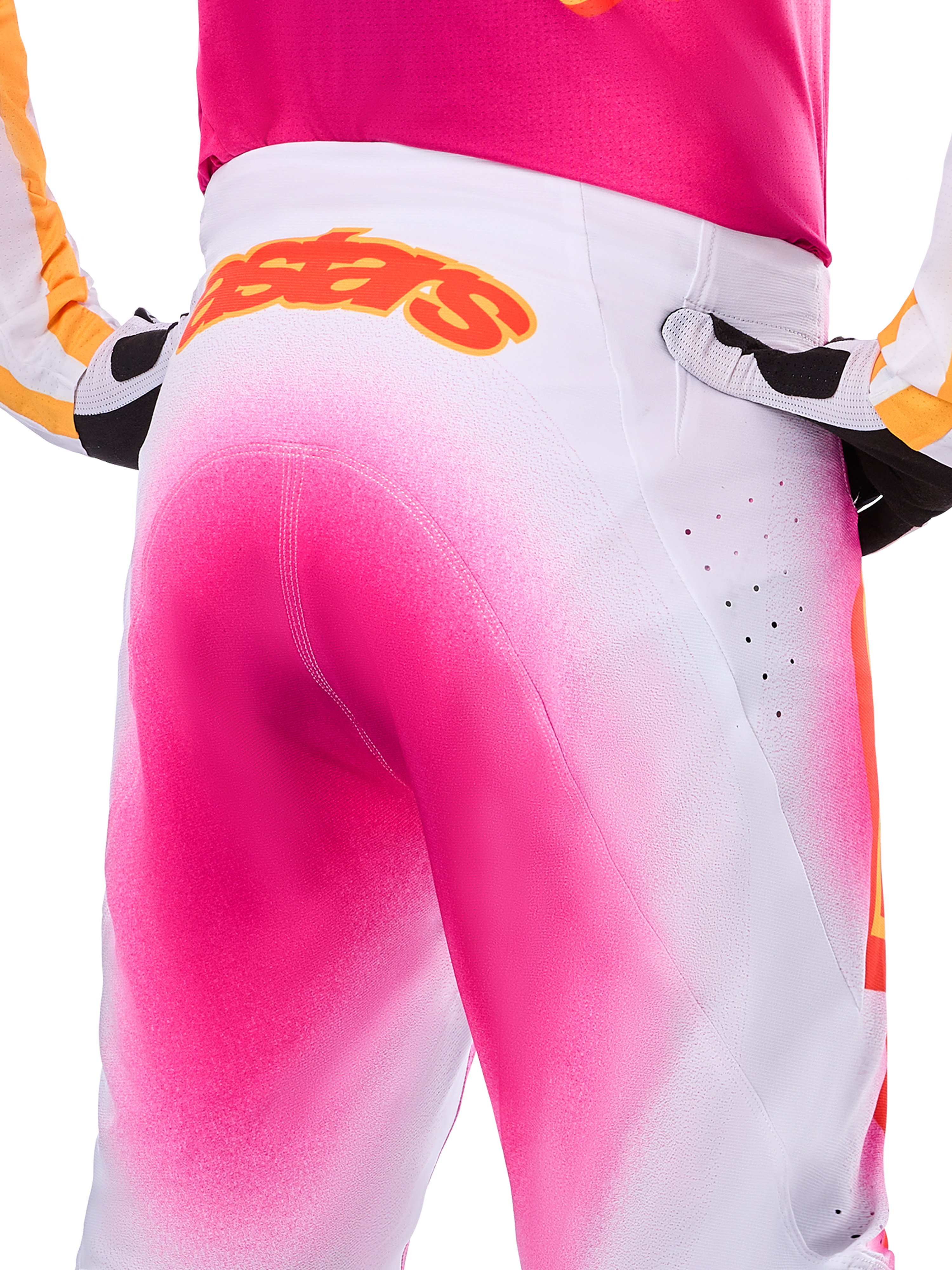 Alpinestars Limited Edition Supertech AFD MIG-byxor, motocrossbyxor, rosa fluo och vita med spraymålad fade-effekt, stor orange Alpinestars-logotyp på bakre linningen, närbild som visar atletisk passform och ventilationsperforeringar.
