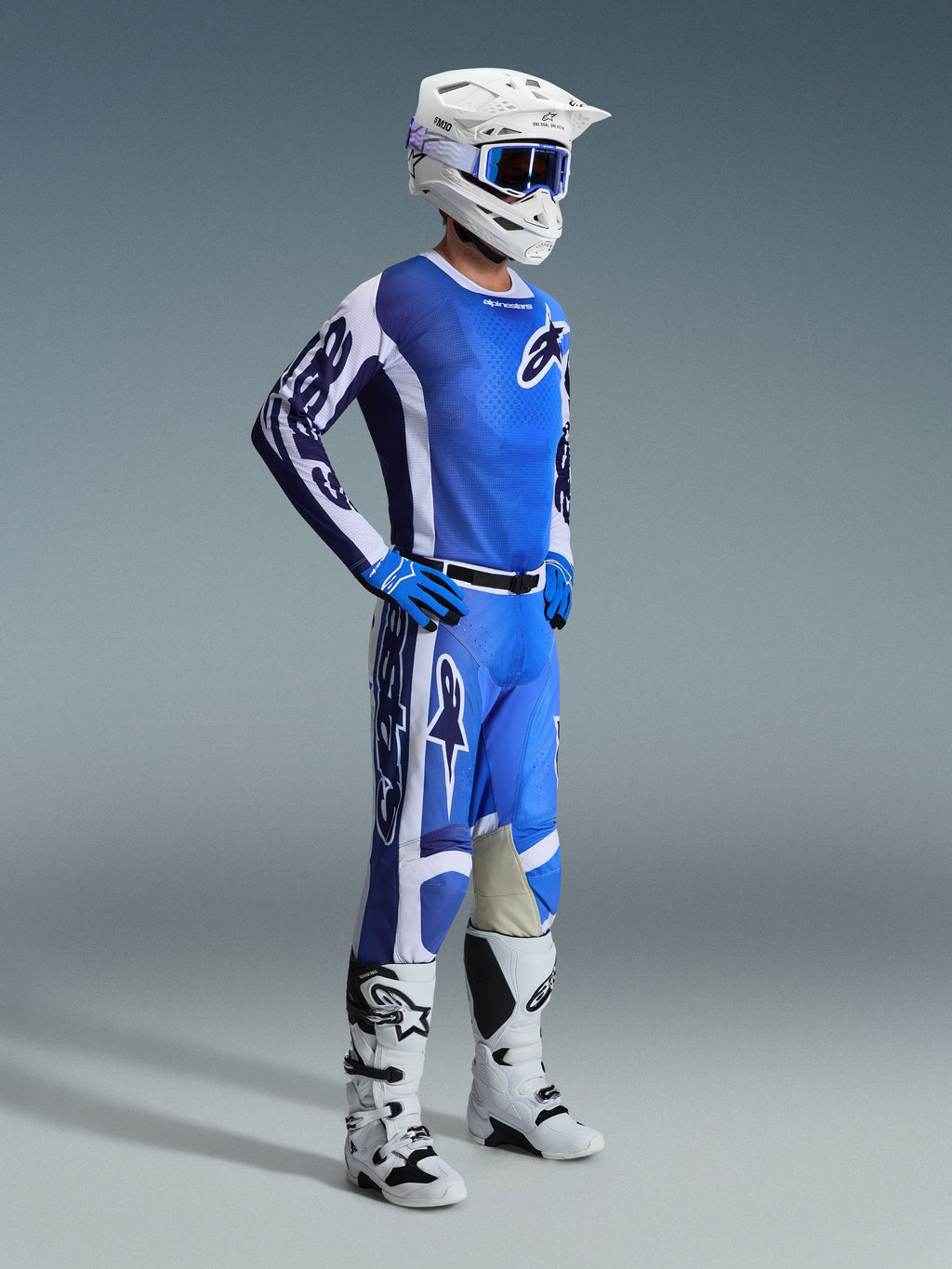 Motocross rider wearing 2026 Racer Air Portl Pants in Ucla Blue White, paired with a matching blue and white jersey, white helmet with blue goggles, and white boots, full gear set for off-road racing.