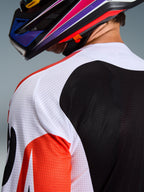 Alpinestars 2026 Racer Air Portl-tröja, motocrosströja, flerfärgad med vita, svarta och röda paneler, närbild på den perforerade mesh-konstruktionen på axeln och ryggen för ventilation, bärs med en färgstark motocrosshjälm