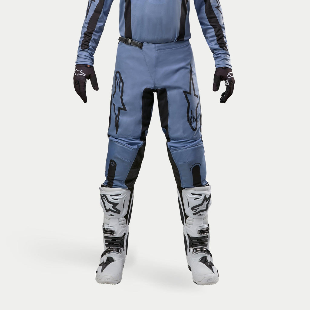 Alpinestars 2024 Fluid Lurv Pants, Motocross Pants, Light Blue and Black, worn with white and black racing boots and matching gloves, featuring bold black star logos on the thighs, ergonomic design for off-road performance