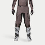 Alpinestars 2024 Fluid Lurv Pants, Motocross Pants, Mud Black, worn with matching jersey, black gloves, and white boots, featuring large black logos on thighs, ergonomic fit, and durable material for off-road racing