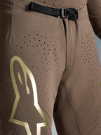 Alpinestars Supertech Air Gold, bruna motocrossbyxor med guldlogotyp, perforerat material och SX1-magnetspänne.