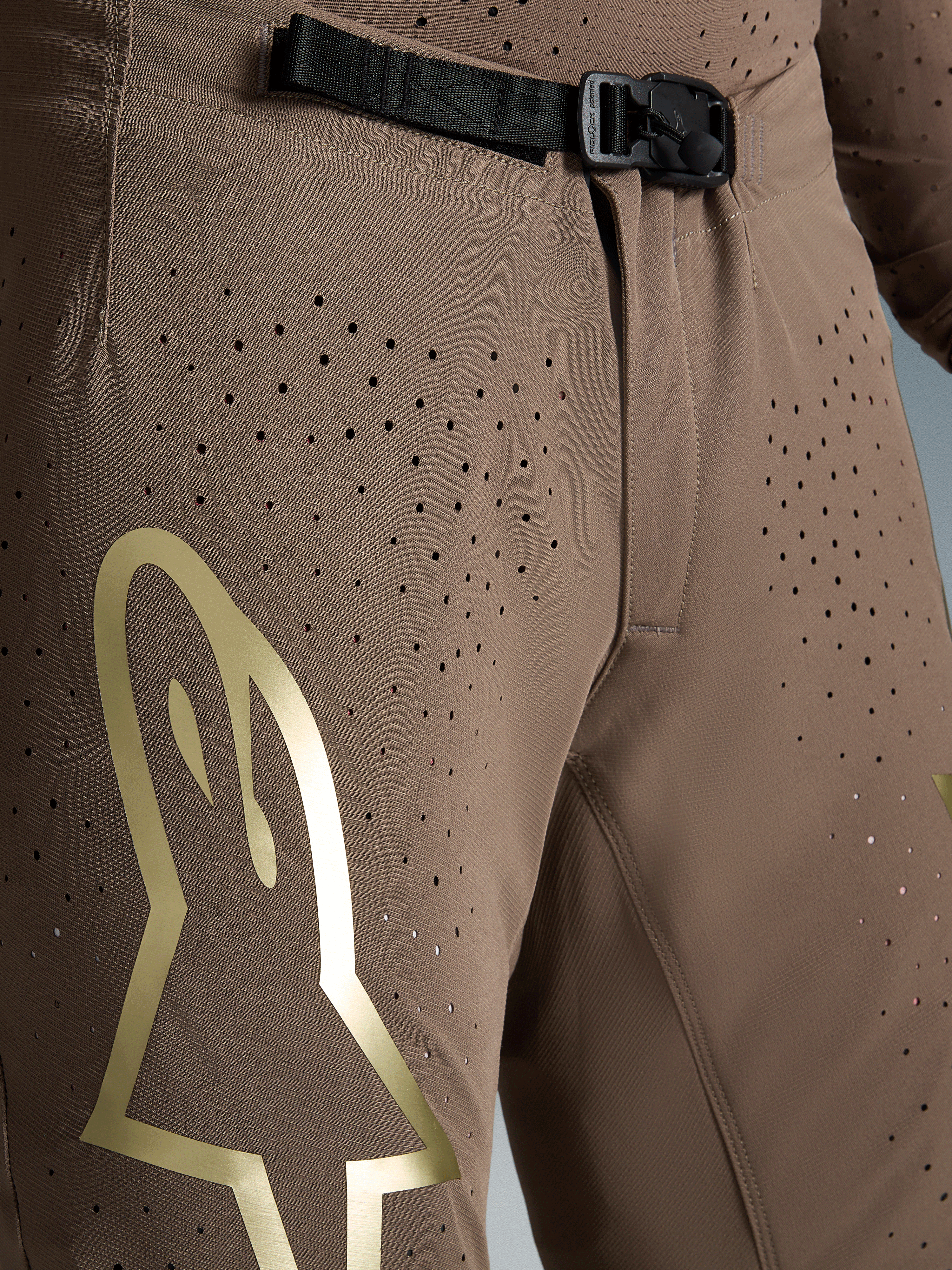 Alpinestars Supertech Air Gold, bruna motocrossbyxor med guldlogotyp, perforerat material och SX1-magnetspänne.