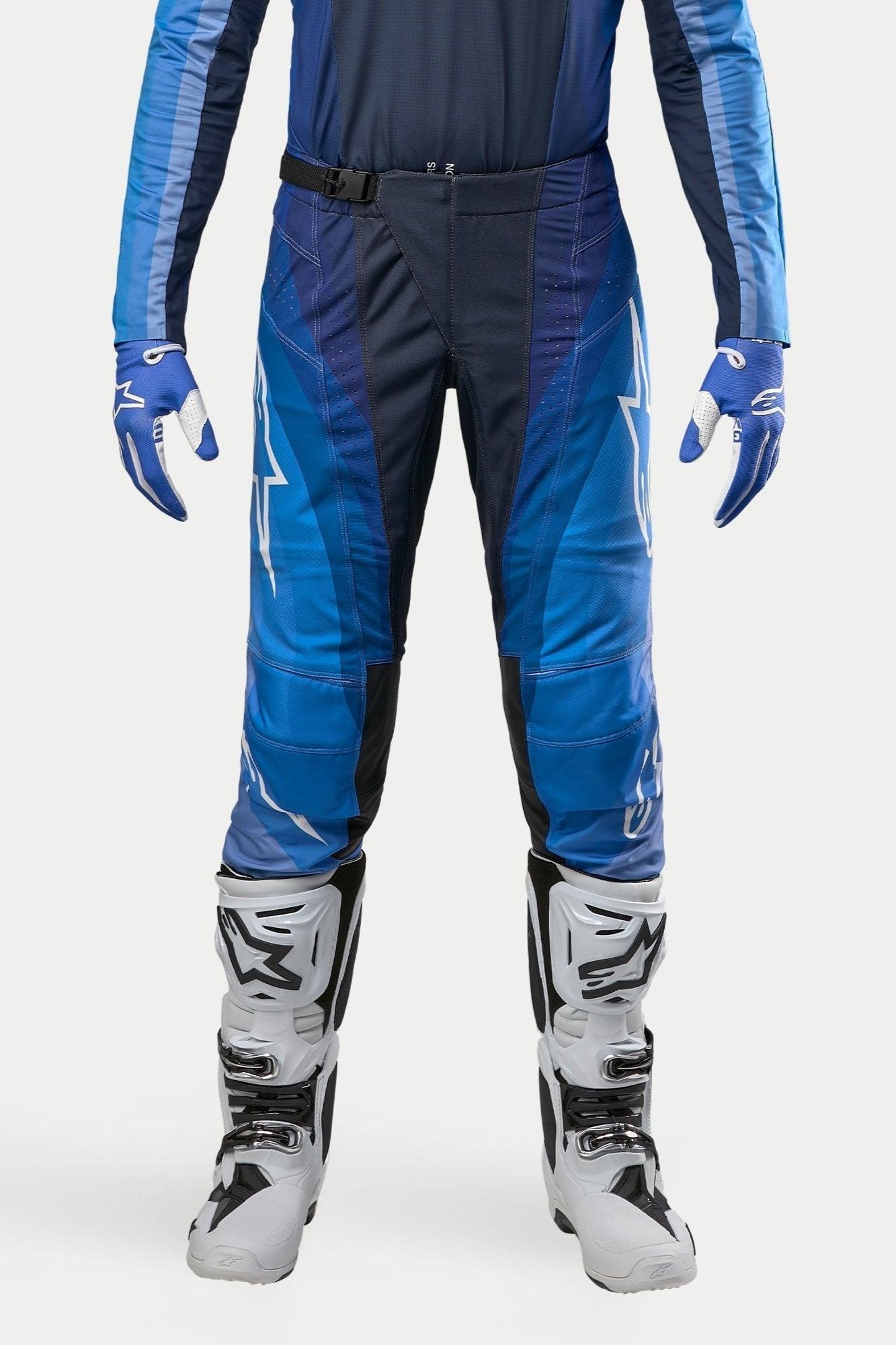 Alpinestars 2024 Techstar Pneuma-byxor, motocrossbyxor, mörkblå och ljusblå, bärs med matchande blå tröja och vita stövlar, med vit Alpinestars-logotyp och magnetspänne, designade för professionell terrängkörning