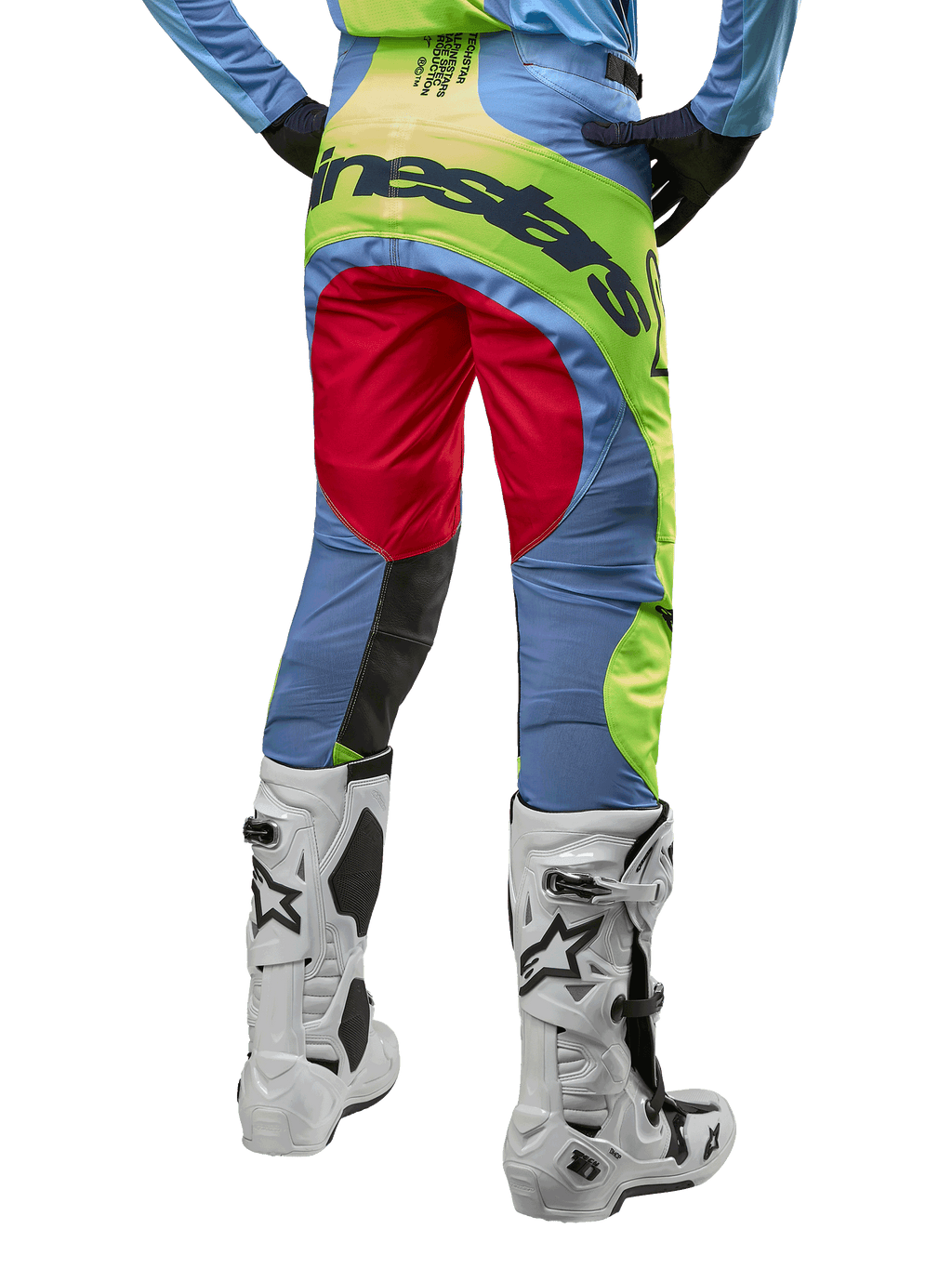 Alpinestars 2024 Techstar Ocuri-byxor, motocrossbyxor, ljusblå, neongula och bärröda, vy bakifrån bärs med vita och svarta motocross-stövlar, med livfull color-blocking och tydlig Alpinestars-logotyp på sätet.