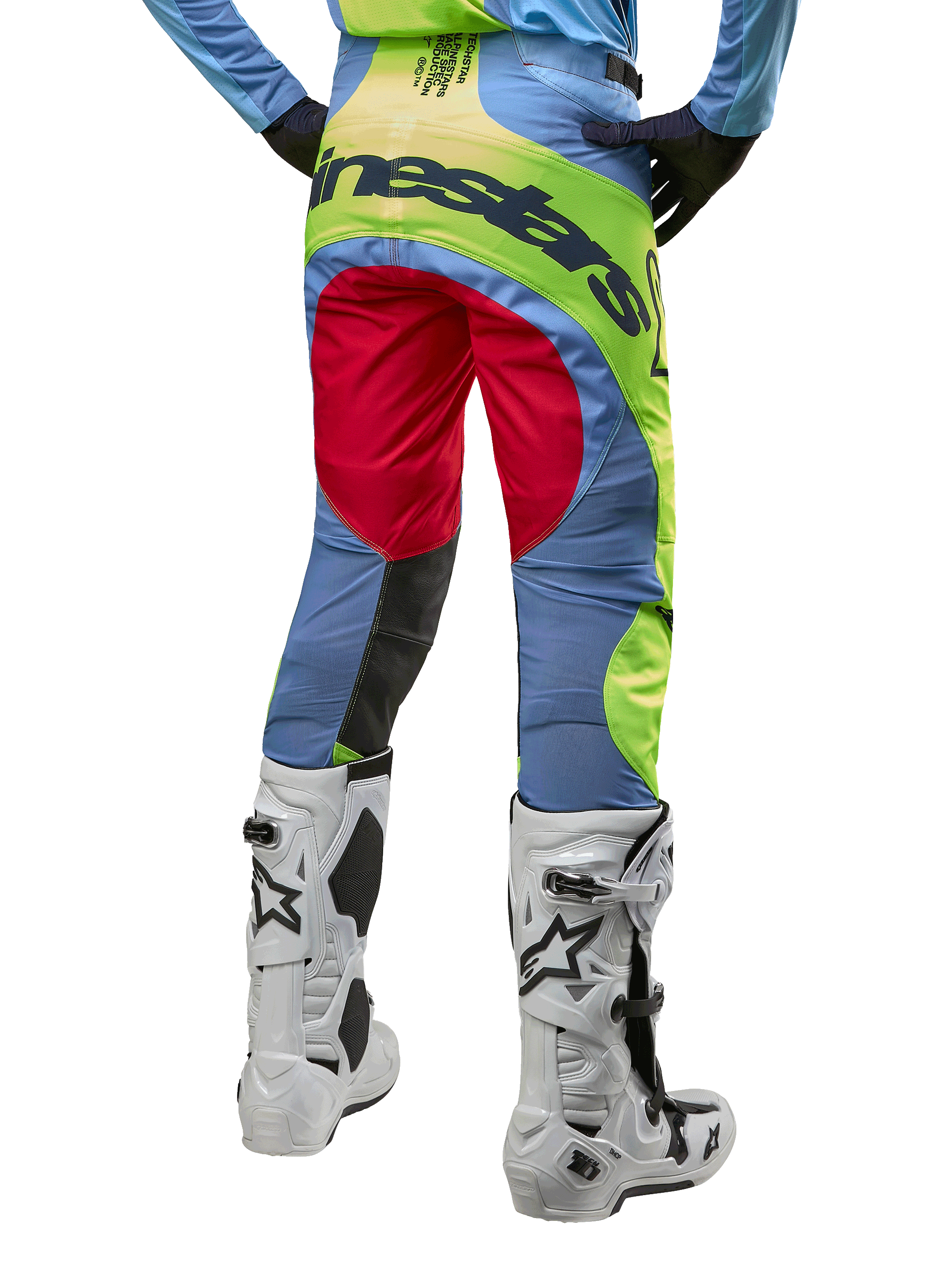Alpinestars 2024 Techstar Ocuri-byxor, motocrossbyxor, ljusblå, neongula och bärröda, vy bakifrån bärs med vita och svarta motocross-stövlar, med livfull color-blocking och tydlig Alpinestars-logotyp på sätet.
