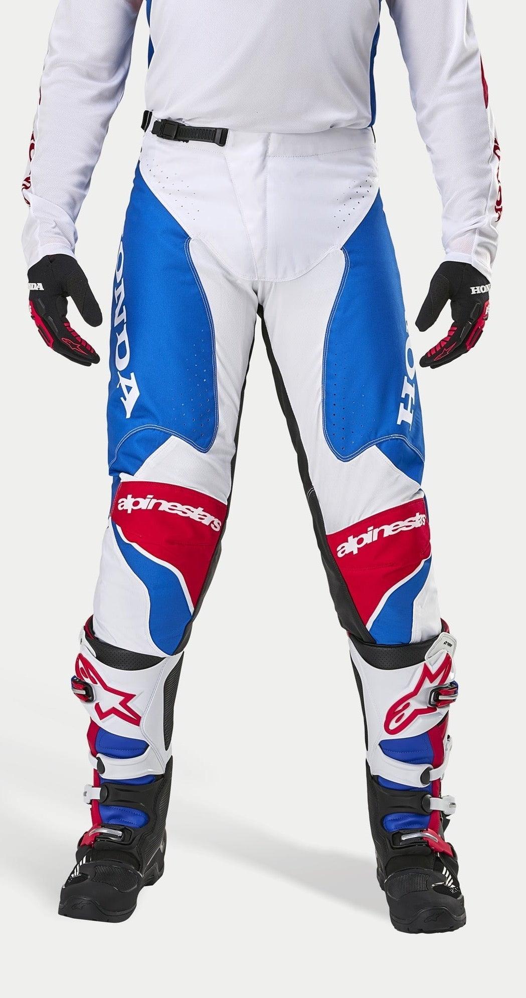 Alpinestars Honda Racer Iconic Pants, Motocross Pants, White Bright Blue and Bright Red, featuring large Honda branding on the side panels and Alpinestars logo on the knees, worn with matching jersey, black gloves, and motocross boots, designed for off-road racing performance.
