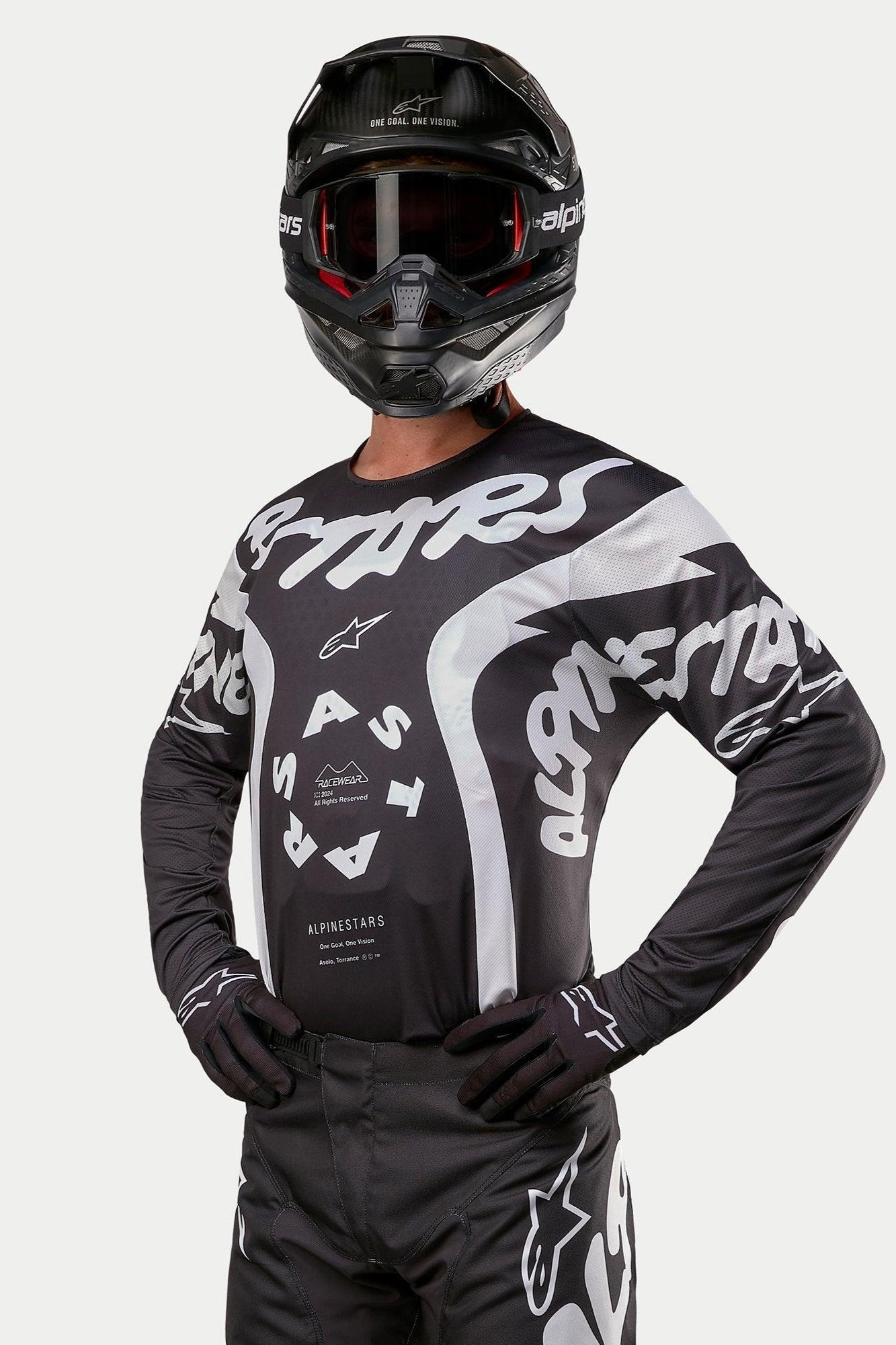 Alpinestars 2024 Racer Hana Jersey, Motocross Jersey, Black and White, featuring bold white Alpinestars text graphics and logo, worn by a rider with a black helmet and goggles, high-performance gear for off-road racing